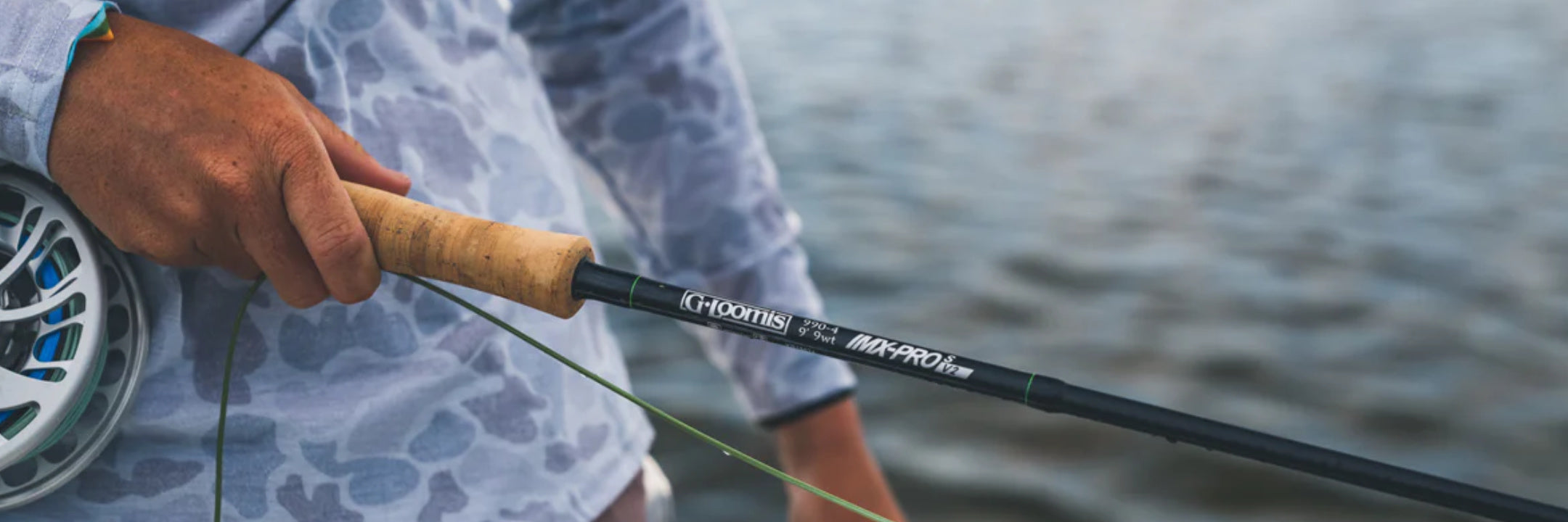 Fly angler holding a G.Loomis IMX-PRO V2S saltwater fly rod above the water