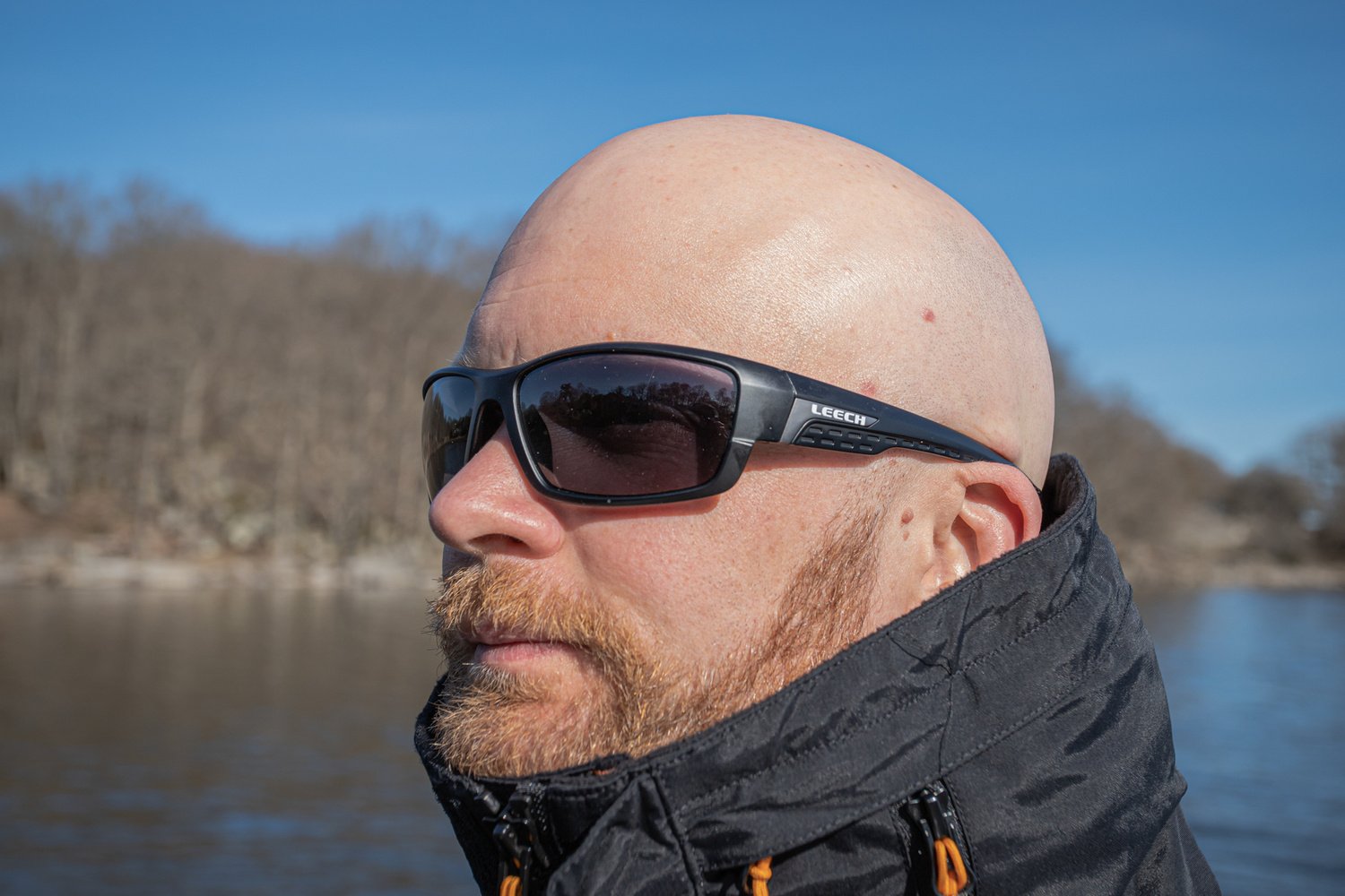 Angler wearing Leech H4X Black photochromic polarized sunglasses near the water on a sunny day.