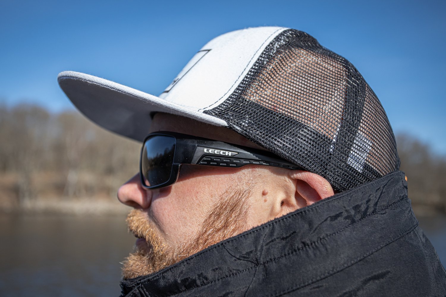 Side profile of an angler wearing Leech H4X Black photochromic polarized sunglasses outdoors.