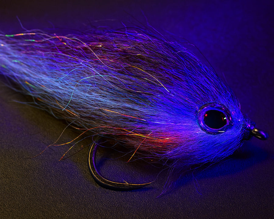 UV-reactive streamer fly tied from Sybai Natural Pike Supreme Hair, macro studio shot with visible fiber texture and UV glow
